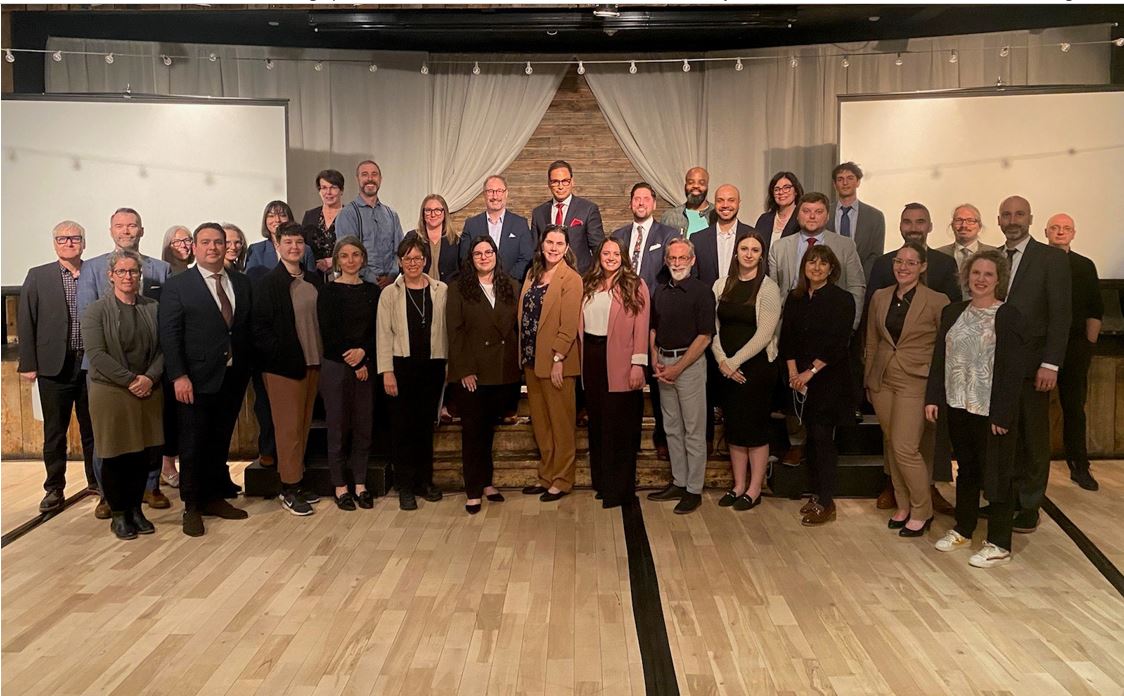  A group of 33 people who participated in the Advisory Committee on Access to Justice in Both Official Languages standing together in a conference room at their annual meeting in Canmore, Alberta.