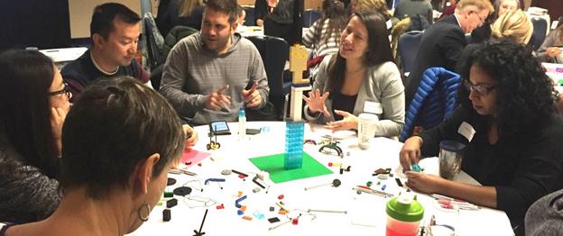 Group of people at a table with scattered lego pieces.